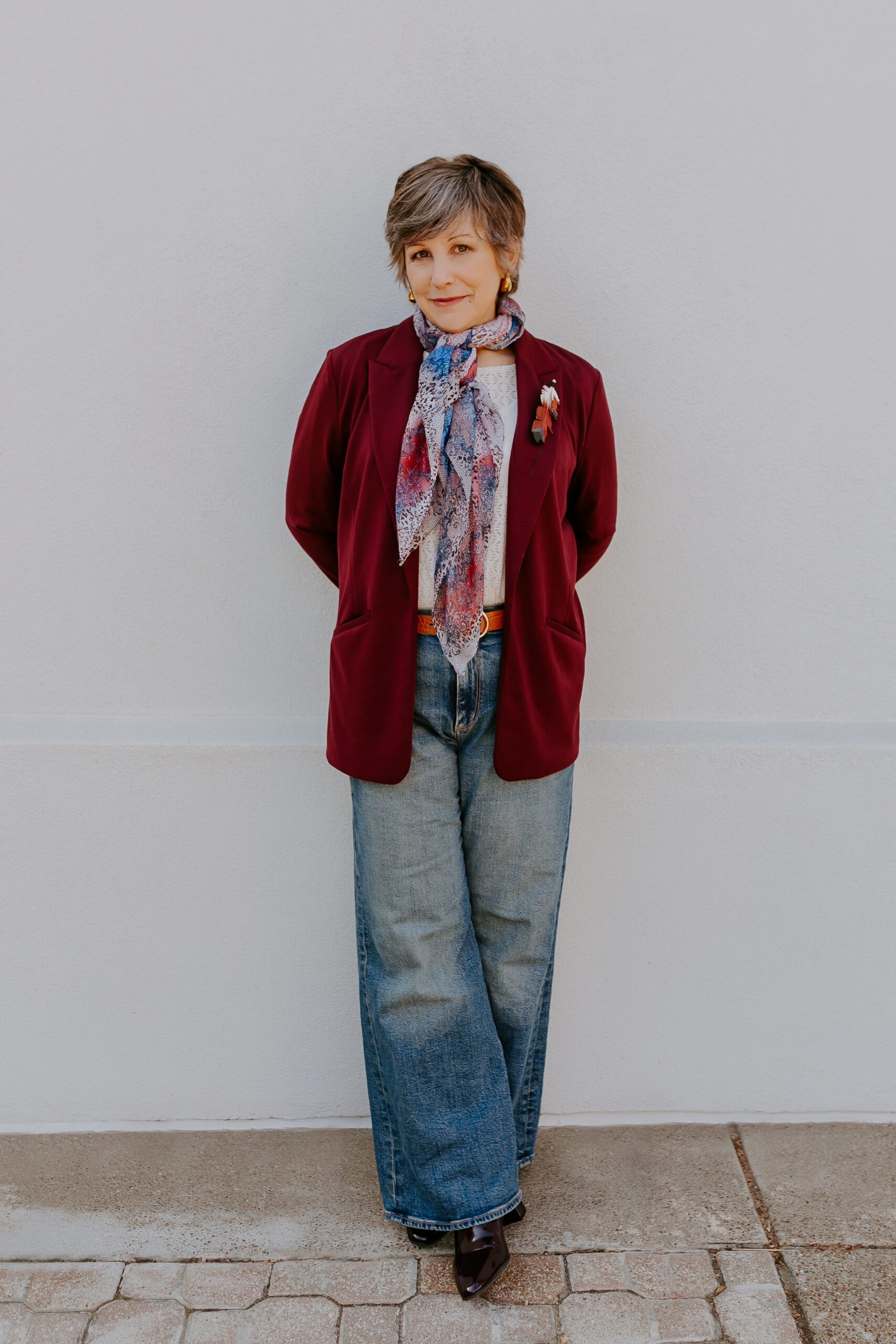 Full-body photo of a person standing against a plain wall.